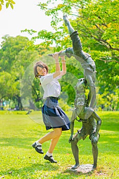 Cute Thai schoolgirl is jumping with a statue