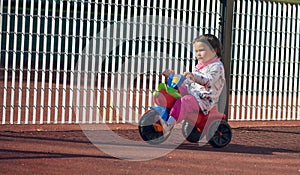 Cute three-year-old little child riding a 3-wheel bike in playground