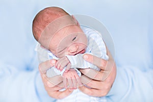Cute tiny newborn baby boy in his father's hands