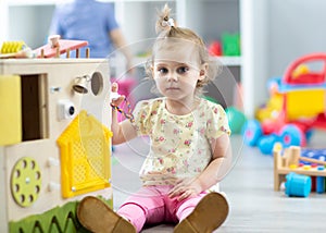 Cute toddler baby playing with busy board in daycare. Children`s educational toys.