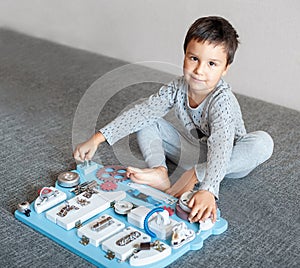 Cute toddler baby playing with busy board at home