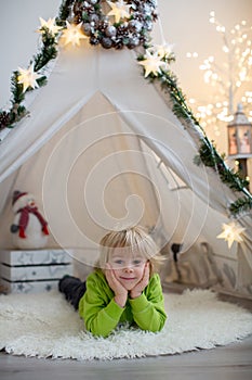 Cute toddler blond child in front of a teepee with pet dog, lying on the floor with sign love