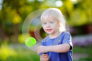 Cute toddler boy with big green lollipop