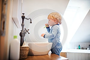 Cute toddler boy brushing his teeth in the bathroom.