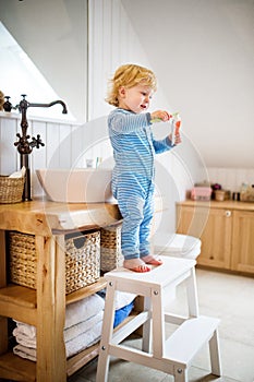 Cute toddler boy brushing his teeth in the bathroom.