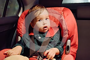 Cute toddler boy is in car seat. Portrait of pretty little child during family road trip. Kid scared by motion sickness or riding