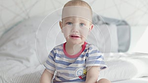 cute toddler boy child sad face portrait crying moody kid sitting in bed daytime