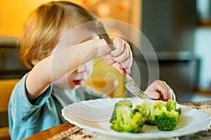 Cute toddler boy eating broccoli. First solid foods. Fresh organic vegetables for infants. Healthy nutrition for the family