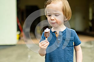 Cute toddler boy eating tasty fresh ice cream outdoors on warm sunny summer day. Children eating sweets