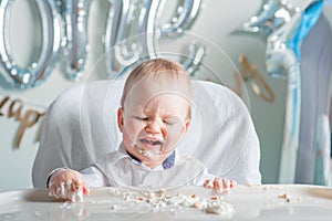 Cute toddler boy for first year of birth eating birthday cupcake with 1 candle close-up and copy space