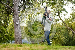 Cute toddler boy helping to harvest apples in apple tree orchard in summer day. Child picking fruits in a garden. Fresh healthy