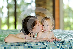 Cute toddler boy and his mother having fun in indoor pool. Child learning to swim. Kid having fun with water toys. Family fun in a