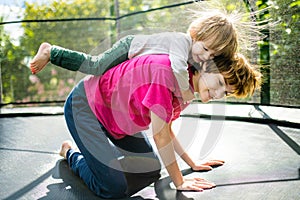 Cute toddler boy and his sister jumping on a trampoline in a backyard. Sports and exercises for children. Summer outdoor