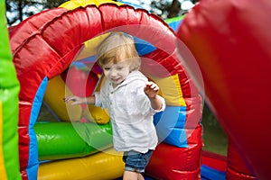 Cute toddler boy jumping on a inflatable bouncer in a backyard on warm and sunny summer day. Sports and exercises for children
