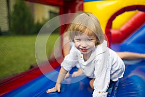 Cute toddler boy jumping on a inflatable bouncer in a backyard on warm and sunny summer day. Sports and exercises for children