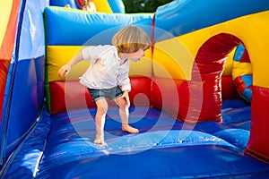 Cute toddler boy jumping on a inflatable bouncer in a backyard on warm and sunny summer day. Sports and exercises for children