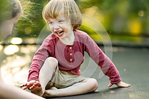 Cute toddler boy jumping on a trampoline in a backyard on warm and sunny summer day. Sports and exercises for children