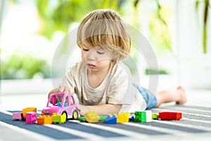 Cute toddler boy playing with blocks construction toy set on the floor at home. Daytime care creative activity. Kids having fun