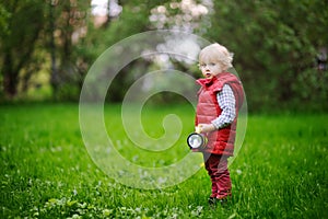 Cute toddler boy playing outdoors at cold summer or spring day