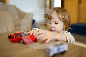 Cute toddler boy playing with red toy car. Small child having fun with toys. Kid spending time in a cozy living room at home