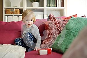 Cute toddler boy playing with red toy car. Small child having fun with toys. Kid spending time in a cozy living room at home