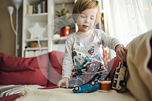 Cute toddler boy playing with toy cars. Small child having fun with toys. Kid spending time in a cozy living room at home