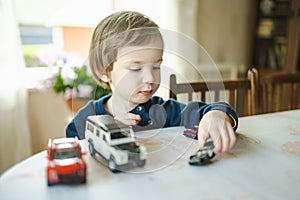 Cute toddler boy playing with toy cars. Small child having fun with toys. Kid spending time in a cozy living room at home