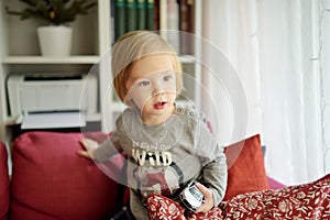 Cute toddler boy playing with white toy car. Small child having fun with toys. Kid spending time in a cozy living room at home