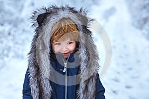 Cute toddler boy playing in winter park in snow outdoors. Boy dreams of winter time. Well dressed enjoying the winter