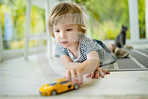 Cute toddler boy playing with yellow toy car. Small child having fun with toys. Kid spending time in a cozy living room at home