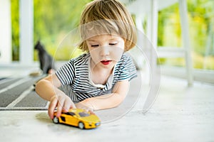Cute toddler boy playing with yellow toy car. Small child having fun with toys. Kid spending time in a cozy living room at home