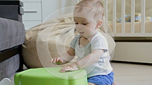 Cute toddler boy sitting on floor at living room and playing on drums