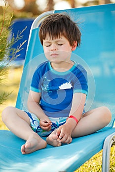Cute toddler boy sitting on a sunbed