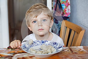 Cute toddler boy of three years eating pasta at home kitchen