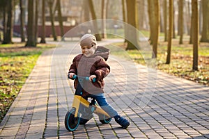 A cute toddler boy of three years old rides a bicycle or balance bike