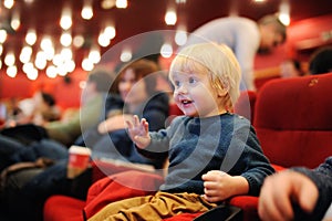 Cute toddler boy watching cartoon movie in the cinema