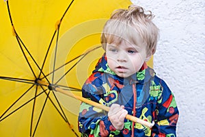 Cute toddler boy with yellow umbrella, outdoors