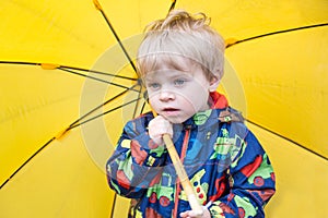 Cute toddler boy with yellow umbrella, outdoors