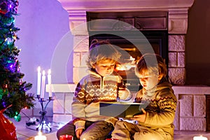 Cute toddler boys, blond twins playing together and opening surprise gift box on Christmas