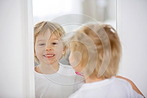 Cute toddler child, blond boy, brushing his teeth at home