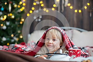 Cute toddler child, boy in a Christmas outfit, playing in a wooden cabin on Christmas, decoration around him