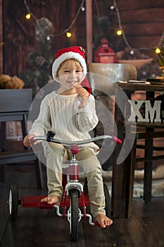 Cute toddler child, boy on Christmas, writing letter to Santa Claus and eating cookies at home, wooden cottage