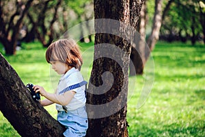 Cute toddler child boy with long hair in stylish outfit playing with toy car on the walk in summer