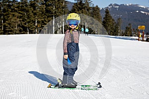 Cute toddler child in colorful ski wear, skiing in Italy on a sunny day, kids and adults skiing together