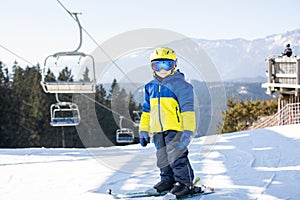 Cute toddler child in colorful ski wear, skiing in Italy on a sunny day, kids and adults skiing together