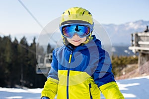 Cute toddler child in colorful ski wear, skiing in Italy on a sunny day, kids and adults skiing together