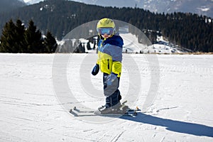 Cute toddler child in colorful ski wear, skiing in Italy on a sunny day, kids and adults skiing together