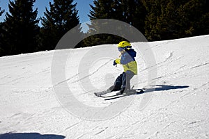 Cute toddler child in colorful ski wear, skiing in Italy on a sunny day, kids and adults skiing together