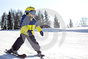 Cute toddler child in colorful ski wear, skiing in Italy on a sunny day, kids and adults skiing together