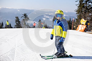 Cute toddler child in colorful ski wear, skiing in Italy on a sunny day, kids and adults skiing together